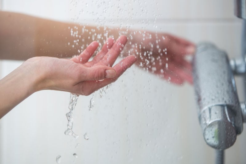 WH_A_005 Should I Get a Tankless Water Heater? Woman's hands feeling the temperature of the shower water.