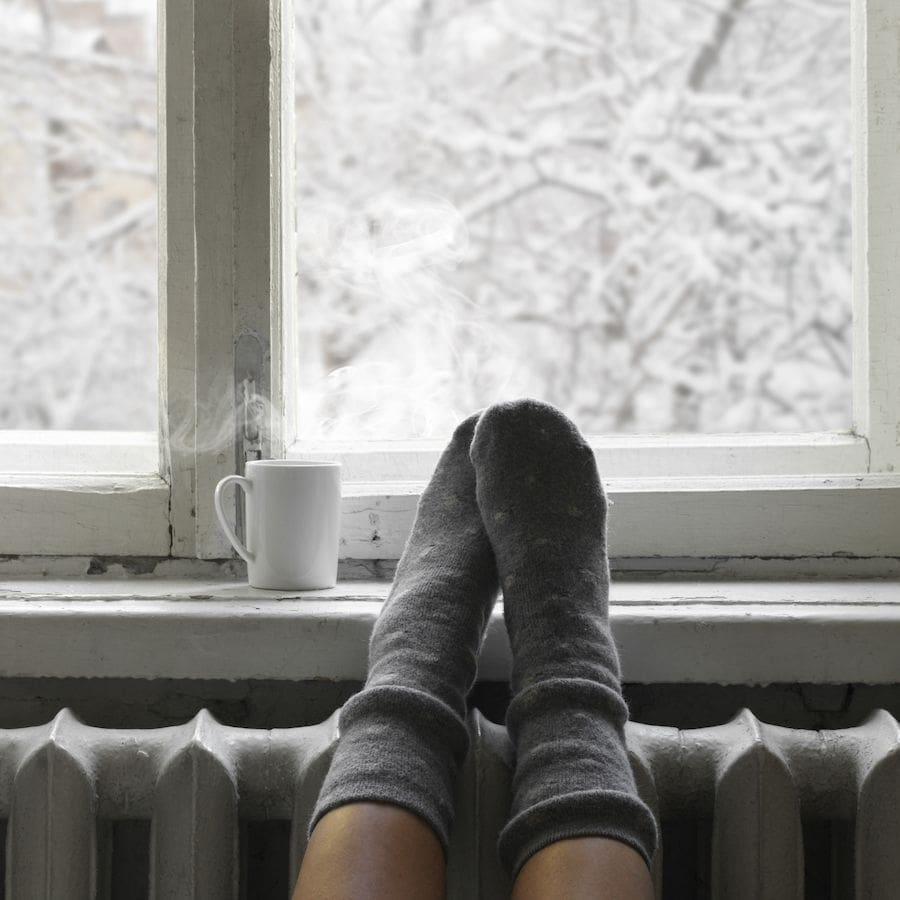 A person with socks warms up. How to Insulate Your Home and Prevent Heat Loss.