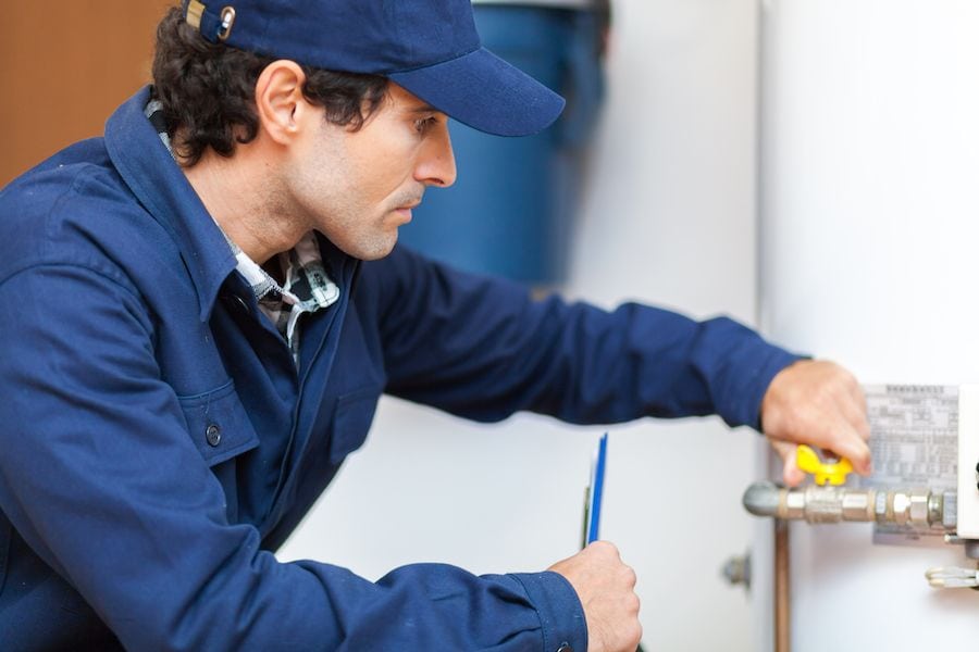 Image of someone working on a water heater. 7 Things you should know about tankless water heaters.